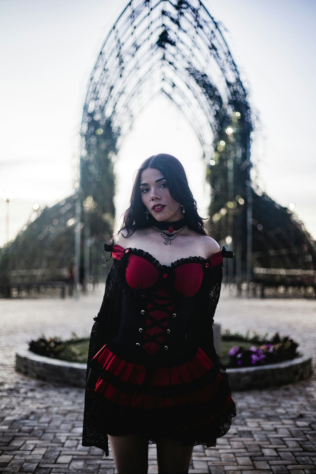 Woman in gothic dress stands in park archway