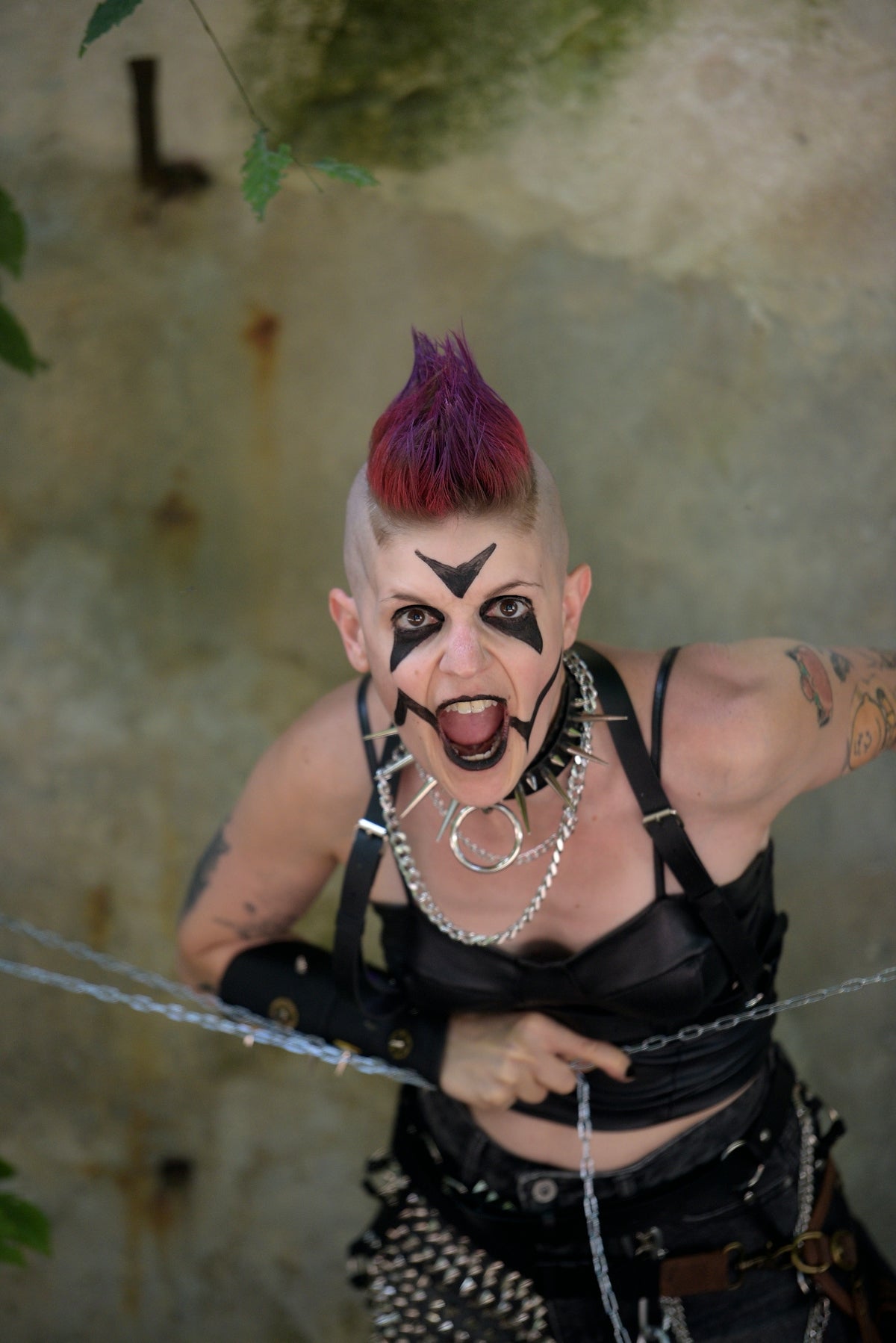 Person with purple mohawk, intense face paint, and punk fashion.