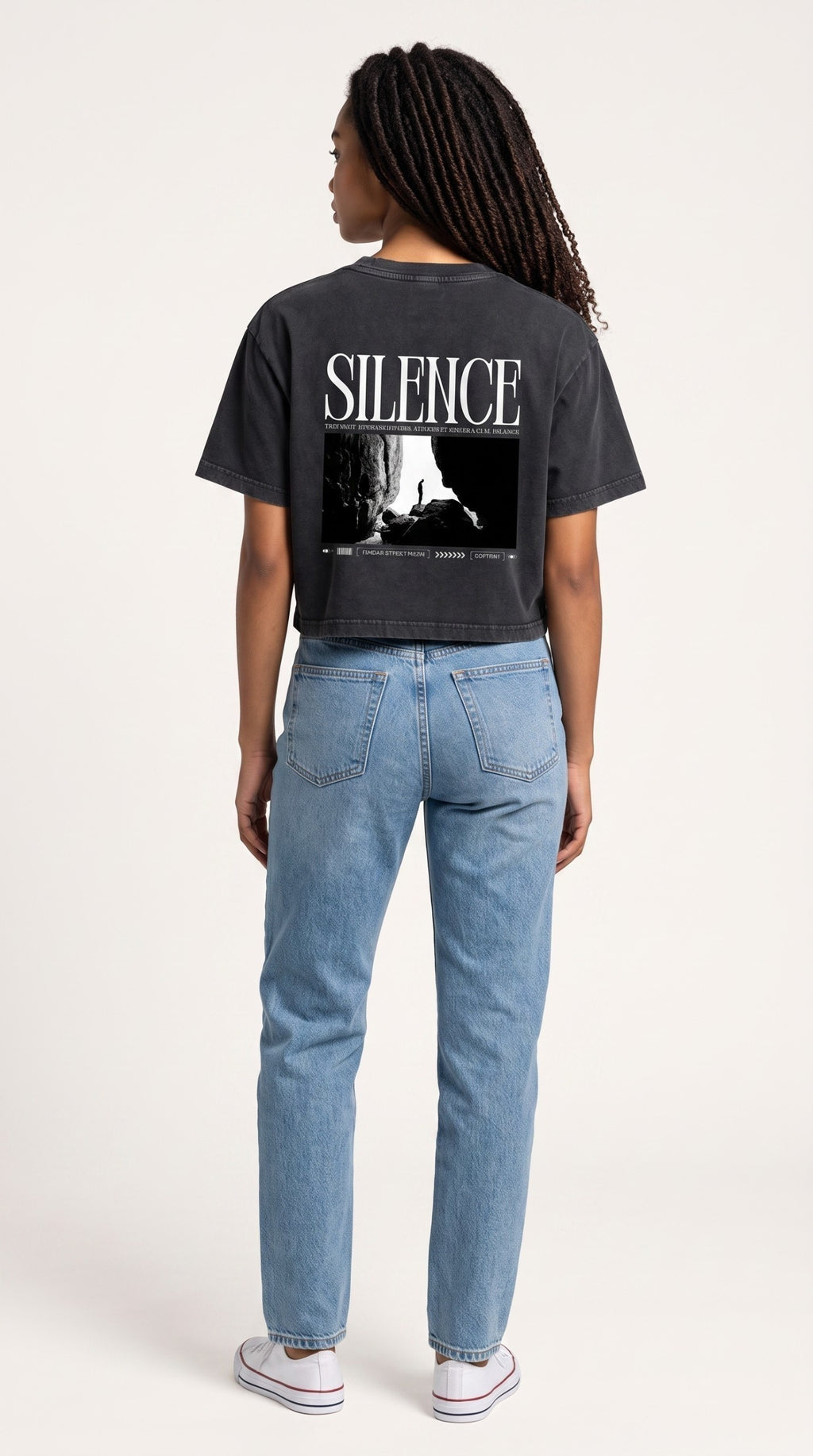Back view of a woman wearing an ALTRD Apparel black mineral wash cotton crop t-shirt with a Silence graphic print.