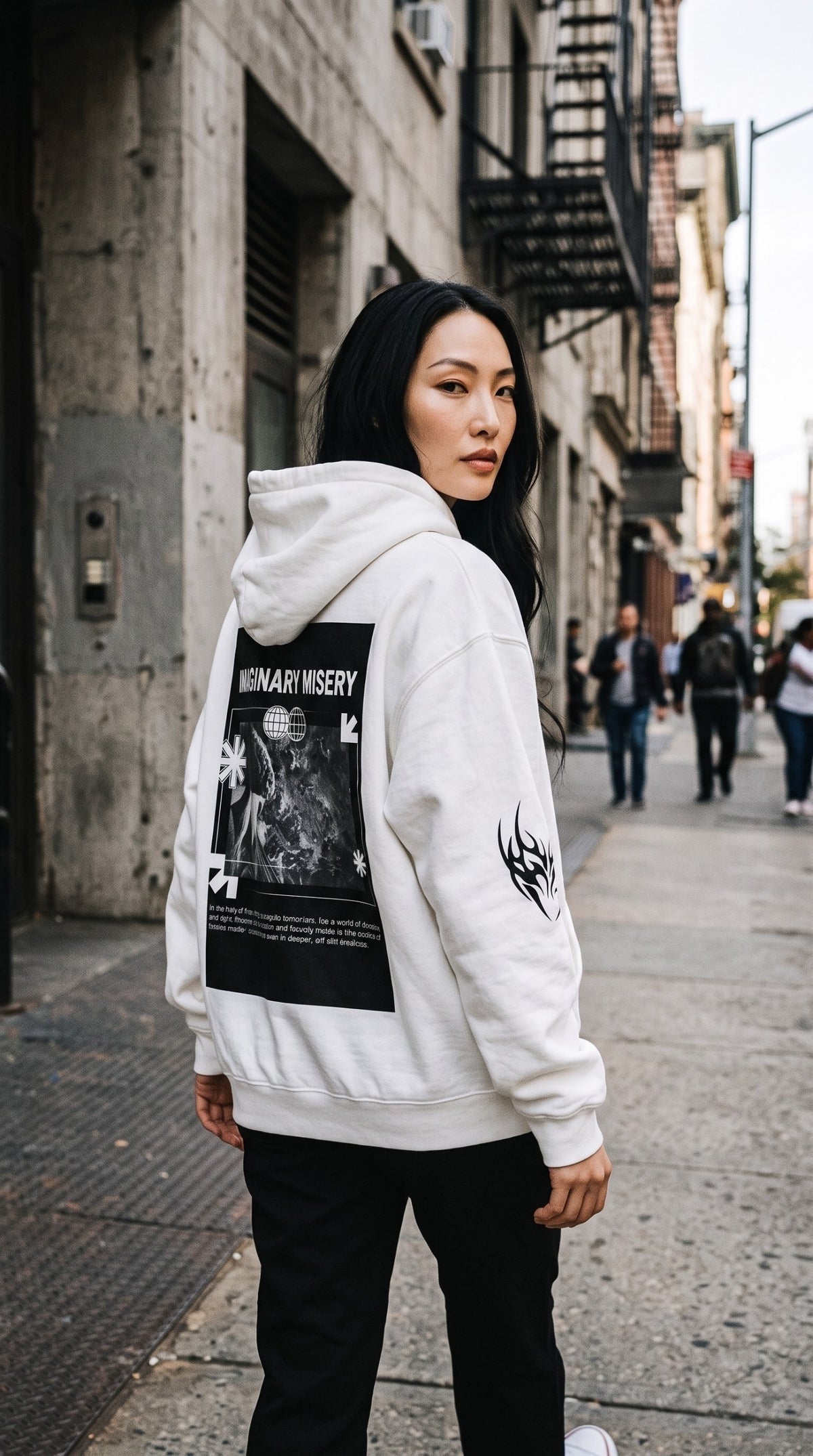 Model wearing an ALTRD Apparel white oversized fleece hoodie with a graphic print on the back on a city street